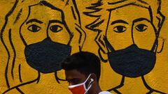 A youth wearing a facemask walk past a mural depicting people wearing famcemaks during the first day of a 21-day government-imposed nationwide lockdown as a preventive measure against the COVID-19 coronavirus, in Mumbai on March 25, 2020. - India&#039;s b