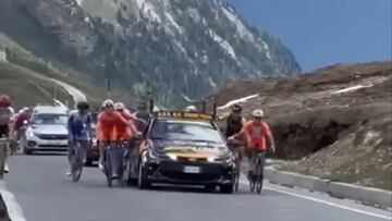 Varios corredores suben agarrados a un coche durante la subida al Stelvio en la cuarta etapa del Giro Next Gen.