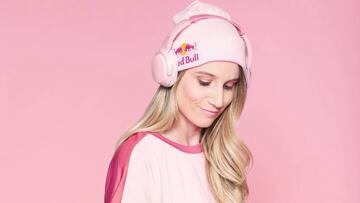 La snowboarder Anna Gasser con fondo rosa, auriculares rosas, gorro rosa de Red Bull y camiseta roja mirando hacia abajo