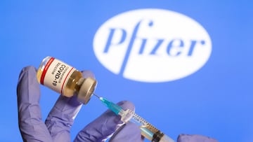 FILE PHOTO: A woman holds a small bottle labeled with a &quot;Coronavirus COVID-19 Vaccine&quot; sticker and a medical syringe in front of displayed Pfizer logo in this illustration taken, October 30, 2020. REUTERS/Dado Ruvic/File Photo