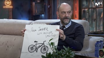 El humorista Javier Cansado, sentado en el sof&aacute; de La Resistencia, en Movistar +, mirando a David Broncano y ense&ntilde;ando un dibujo de una bicicleta el&eacute;ctrica hecho por Jorge Ponce. 