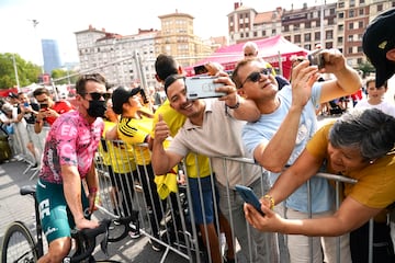 Varias personas se hacen una selfie con un ciclista durante la salida de la sexta etapa de La Vuelta Ciclista a España 2022, desde el estadio de San Mamés.