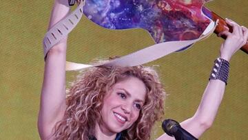 Shakira mostrando su guitarra con la foto de Piqué y sus hijos en su concierto de Ámsterdam.