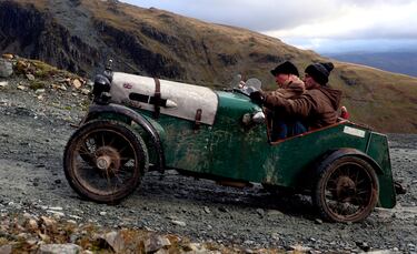 Un auto deportivo antiguo, con sus dos ocupantes, asciende una colina de piedras durante la 53ª edición del VSCC Lakeland Trial, una prueba de carácter anual que reúne a un gran número de aficionados a los coches históricos. El recorrido transcurre por varias colinas próximas a la mina de pizarra Honister, en Keswick (Gran Bretaña).  