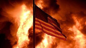 Las llamas envuelven el edificio de la Divisi&oacute;n de Correcciones Comunitarias mientras una bandera estadounidense ondea en un poste y las protestas se convierten en incendios en Kenosha, Wisconsin, EE. UU. El 24 de agosto de 2020.