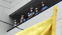 Health workers watch from a balcony as demonstrators pass by with a Colombian flag, during a protest against a tax reform bill launched by Colombian President Ivan Duque, in Medellin, Colombia on April 29, 2021. - Workers&#039; unions, teachers, civil organizations, indigenous people and other sectors reject the project that is underway in the Congress, considering that it punishes the middle class and is inappropriate in the midst of the crisis unleashed by the COVID-19 pandemic. (Photo by JOAQUIN SARMIENTO / AFP)