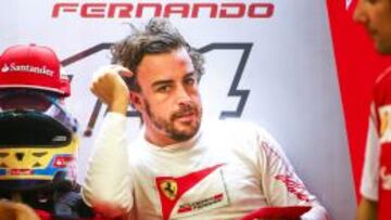 Fernando Alonso descansa en su box durante la primera sesi&oacute;n de libres.