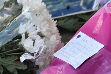 A picture shows hand-written note attached to a bunch of flowers on a growing pile of tributes outside Leicester City