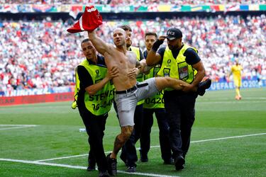 El personal de seguridad del Munich Football Arena retiran a un invasor sobre el terreno de juego.