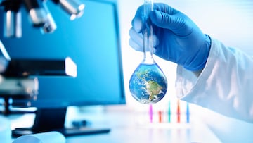 A scientist holding a flask with an image of the earth