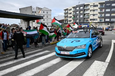 El coche del equipo israelí Premier Tech pasa delante del grupo de protesta a favor de Palestina.