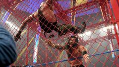 Roman Reigns lanza a Rey Mysterio contra la jaula de Hell in a Cell.