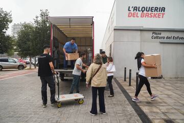 Varias personas llevan cajas con mantas, ropas y objetos de primera necesidad para las personas que se encuentran en el pabellón de baloncesto, 'La Fonteta'.