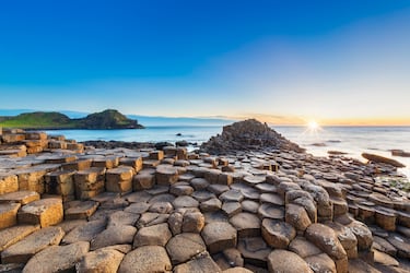 La Calzada del Gigante (Giant’s Causeway), situada en la costa norte de Irlanda del Norte, es un asombroso campo de unas 40,000 columnas de basalto entrelazadas que se formaron hace unos 60 millones de años debido a una intensa actividad volcánica. Geológicamente, estas estructuras son el resultado de una colada de lava que, al enfriarse de manera lenta y uniforme sobre una superficie plana, se contrajo y se fracturó en patrones geométricos casi perfectos, predominantemente hexagonales, un proceso conocido como disyunción columnar.