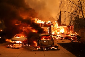 Vehicles and a house burn as powerful winds fueling devastating wildfires in the Los Angeles area 