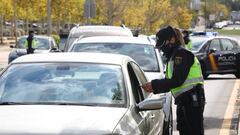 Una agente de la Polic&iacute;a Nacional comprueba la documentaci&oacute;n de un conductor durante un control policial en el segundo d&iacute;a de entrada en vigor de las nuevas restricciones de movilidad en el municipio madrile&ntilde;o de Alcorc&oacute;