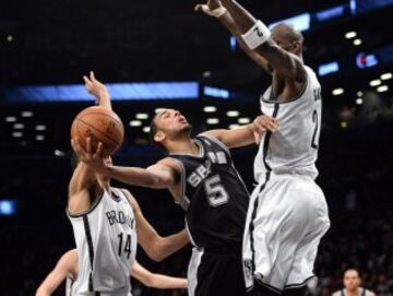 Cory Joseph intenta encestar ante Kevin Garnett durante el Brooklyn-San Antonio.