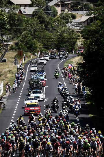 El pelotón adelantando a los vehículos de equipo que transportan las bicicletas. 