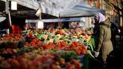 A customer shops for food items at a fruit and vegetable stall at a market in Walthamstow, east London on February 4, 2022.