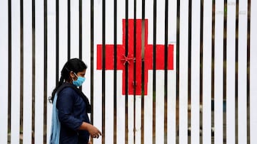 Bangalore (India), 03/07/2020.- An Indian walks in front of the 'ÄòRed Cross'Äô symbol painted on a fence during an extended lockdown over suspected coronavirus disease (COVID-19) cases in Bangalore, India, 03 July 2020. T