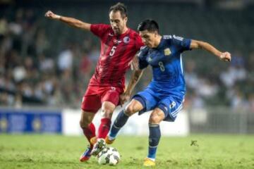 El jugador argentino Enzo Pérez pelea por el control del balón con el jugador de la selección de Hong Kong, Andy Naegelein, durante el partido amistoso disputado en Hong Kong