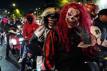 Personas con máscaras recorren las calles en motocicleta durante un desfile de Halloween en la Ciudad de México.