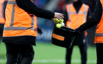 Stadium personnel pick up tennis balls thrown on the pitch during the Bundesliga match between VfL Bochum and FC Bayern Munich.