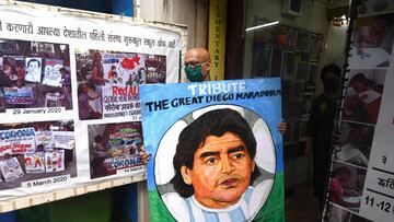 An art teacher carries a painting of late Argentinian football legend Diego Armando Maradona to be displayed as a tribute, outside an art school in Mumbai on November 26, 2020. - Argentinian football legend Diego Maradona passed away on November 25, 2020.