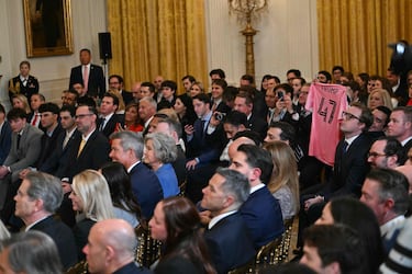 Un asistente sostiene una camiseta Trump del Inter Miami CF mientras el presidente de Estados Unidos habla durante un evento para el Inter Miami CF, ganadores de la Copa de la Major League Soccer 2025, en el Salón Este de la Casa Blanca en Washington.