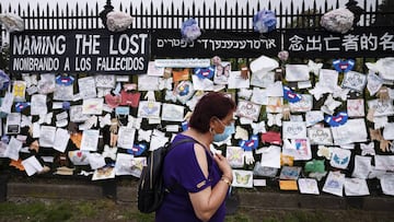 ARCHIVO - En esta foto de archivo del 28 de mayo de 2020, una mujer pasa por una valla frente al cementerio Green-Wood de Brooklyn adornado con tributos a las v&iacute;ctimas del COVID-19 en Nueva York.
 