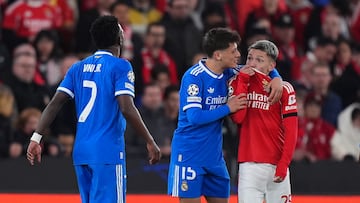 El jugador argentino del Benfica se tapa la boca con la camiseta y algo le dice a Vinicius.