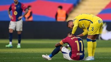 Barcelona's Brazilian forward #11 Raphinha (C) is consoled by Las Palmas' Spanish midfielder #11 Benito Ramirez (R) after their Spanish league football match between FC Barcelona and UD Las Palmas at the Estadi Olimpic Lluis Companys in Barcelona on November 30, 2024. (Photo by Josep LAGO / AFP)