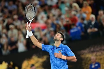 Novak Djokovic celebra su victoria en la final del Open de Australia en el terreno de juego señalando al cielo.