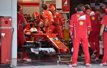 Sebastian Vettel, dentro del coche, espera a que sus mecánicos reparen una avería.