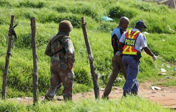 A police officer detains a local as a member of the military looks on during a nationwide lockdown aimed at limiting the spread of the coronavirus disease (COVID-19), in Soweto, South Africa April 23, 2020. REUTERS/Siphiwe Sibeko