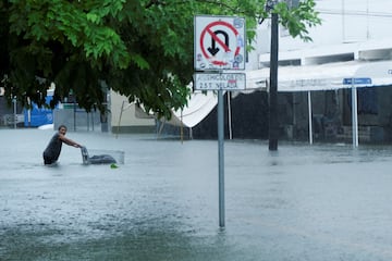 Un hombre empuja un carrito en una calle inundada durante las lluvias provocadas por la tormenta tropical Helene, en Cancún.