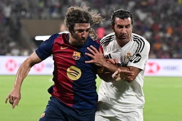 Puyol y Figo pugnan por un balón.