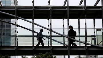 FILE PHOTO: Businessmen wearing protective face masks walk on a pedestrian bridge, amid the spread of the coronavirus disease (COVID-19), in a business district in Tokyo, Japan June 24, 2020. REUTERS/Issei Kato/File Photo