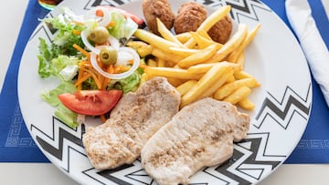 Combo plate in the beach restaurant, an amazing mediterranean dish with salad, pork tenderloin, croquettes and french fries, yummy and healthy beach menu.