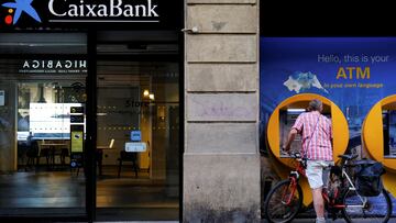 FILE PHOTO: A man uses a Caixabank ATM in Barcelona, Spain, October 3, 2022. REUTERS/Nacho Doce/File Photo