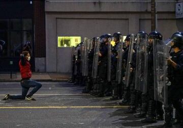 A man gets on his knees in front of police officers during a protest against the death in Minneapolis police custody of African-American man George Floyd, in St Louis, Missouri, US, 1 June 2020.