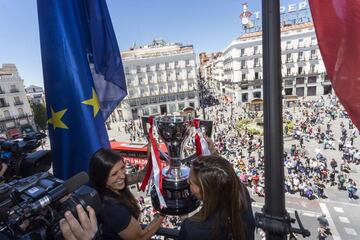 Las jugadoras rojiblancas Jennifer Hermoso y Lola Gallardo ofrecen la Copa de la Liga desde el balcón de la Real Casa de Correos, sede del Gobierno regional. 