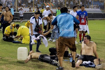 Aficionados heridos reciben ayuda de otros hinchas tras la avalancha en el estadio.