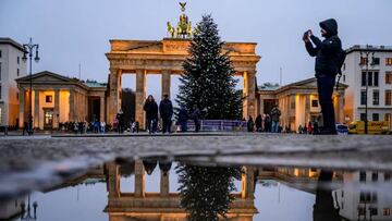The annual Christmas tree stands in front of Berlin's Brandenburg Gate as both are reflected on a puddle and people walk by in Berlin, Germany, on December 6, 2022. - The 2-ton heavy, 15-metre-high fir tree from Thuringia will be illuminated for a shorter period than the previous year, from  4 pm (1500 GMT + 1)  to 10 pm (2100 GMT + 1). (Photo by John MACDOUGALL / AFP) (Photo by JOHN MACDOUGALL/AFP via Getty Images)