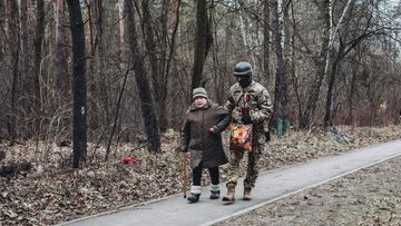 Un soldado ayuda a camina a una anciana bajo el bombardeo, a 6 de marzo de 2022, en Irpin (Ucrania).