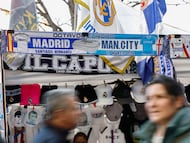MADRID, 11/03/2026.- Varios aficionados pasan junto a un puesto callejero momentos antes del encuentro correspondiente a la ida de los octavos de final de la Liga de Campeones que disputan este miércoles Real Madrid y Manchester City, en el estadio Santiago Bernabéu, en Madrid. EFE/Rodrigo Jiménez