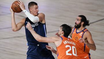 Aug 2, 2020; Lake Buena Vista, USA; Dallas Mavericks forward Kristaps Porzingis, left, looks to pass against Phoenix Suns forward Dario Saric (20) and guard Ricky Rubio, right, during the first half of an NBA basketball game Sunday, Aug. 2, 2020, in Lake Buena Vista, Fla. Mandatory Credit: Ashley Landis/Pool Photo via USA TODAY Sports