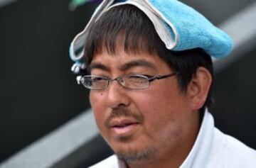 Un espectador se protege de la lluvia debajo de una toalla durante el partido de cuartos de final entre el suizo Roger Federer y el francés Gilles Simon en Wimbledon