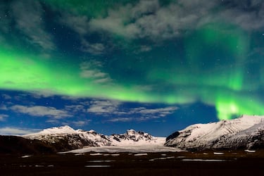 Auroras verdes sobre las montañas en el cielo invernal de Islandia.