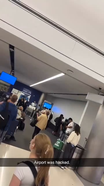Un pasajero en el aeropuerto muestra ccon preocupación las pantallas azules en los ordenadores.